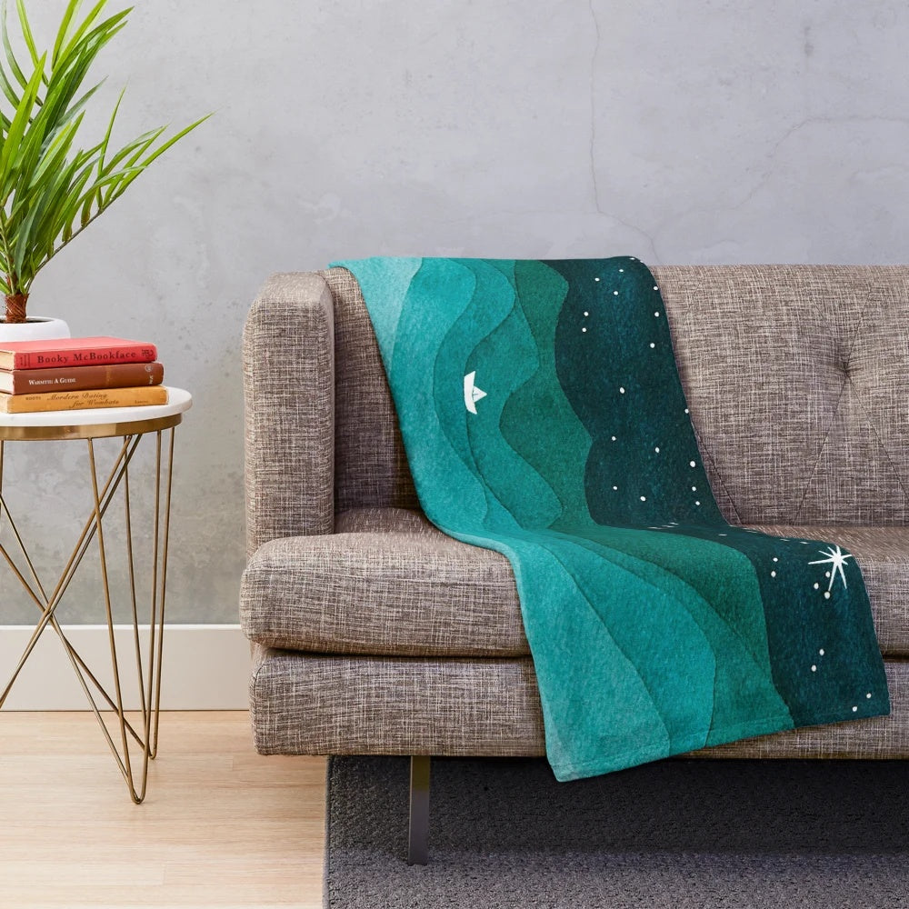 Plush blanket with a starry ocean watercolor design featuring a teal sailboat