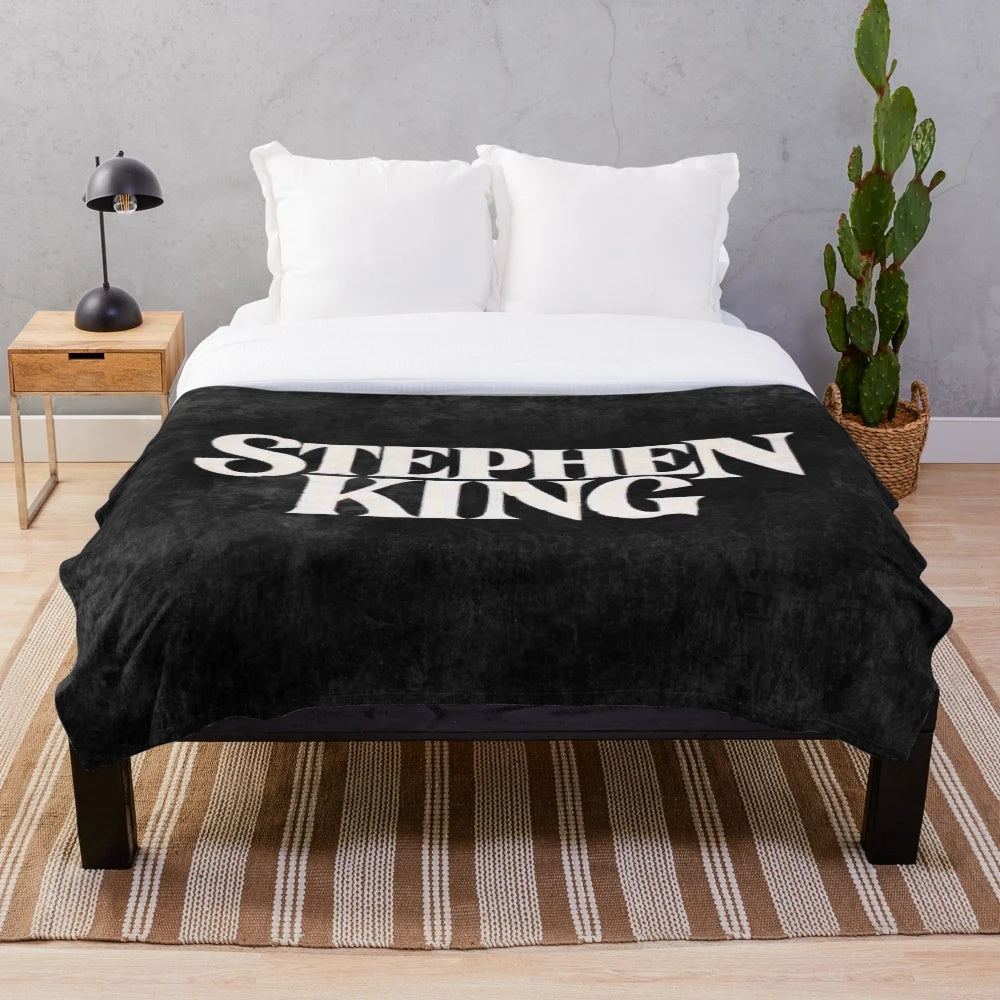 Stephen King-inspired plush blanket featuring book covers and horror movie imagery