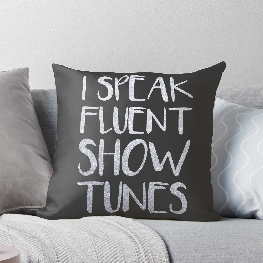 A plush pillow featuring the text "I Speak Fluent Showtunes" against a theatre-inspired background.