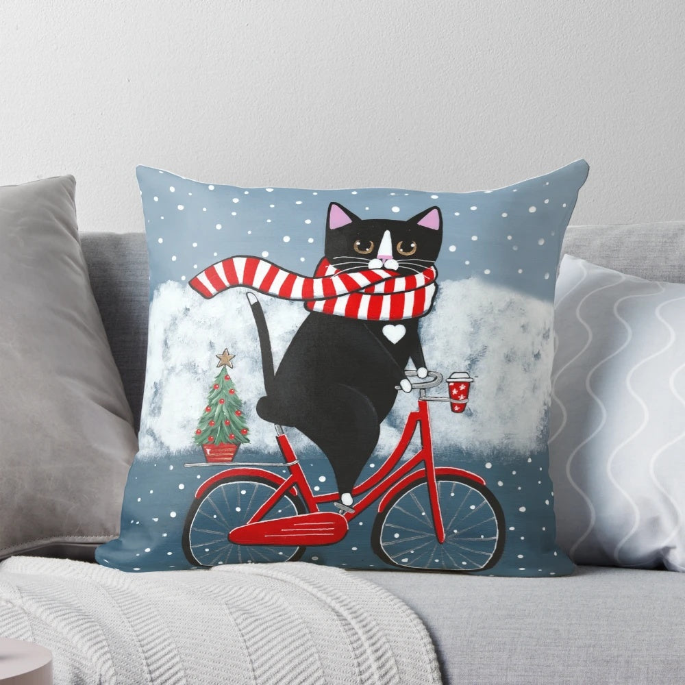 Whimsical tuxedo cat riding a bicycle through a snowy winter scene, printed on a decorative throw pillow.