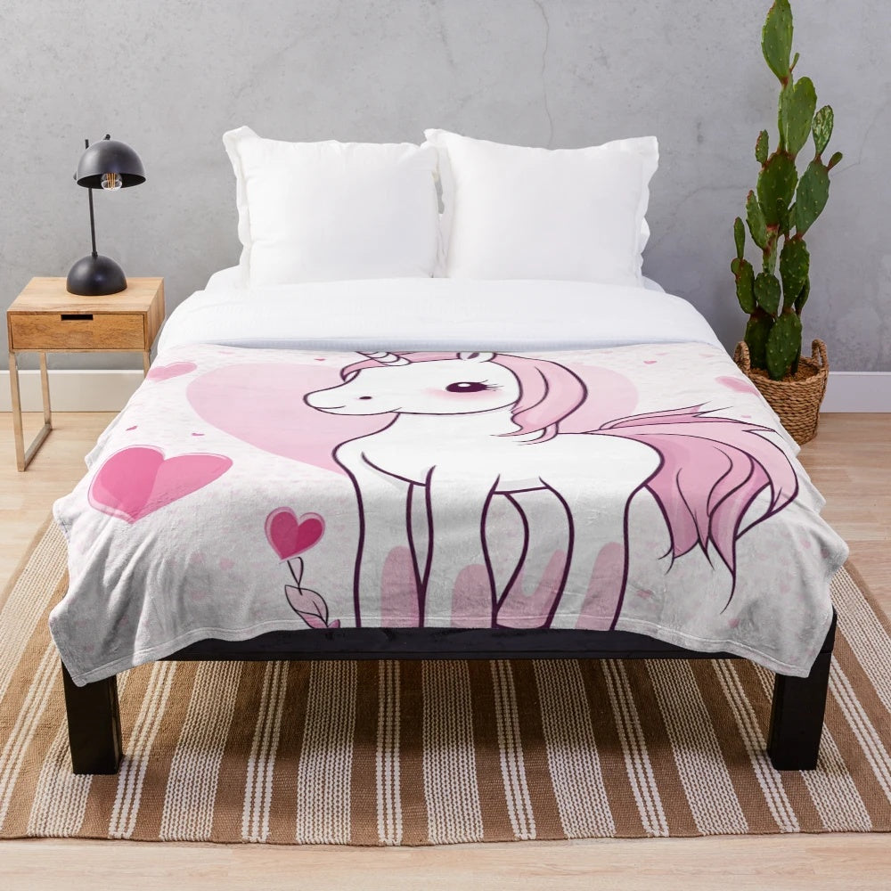 Soft and cuddly pink plush blanket featuring whimsical unicorns and hearts