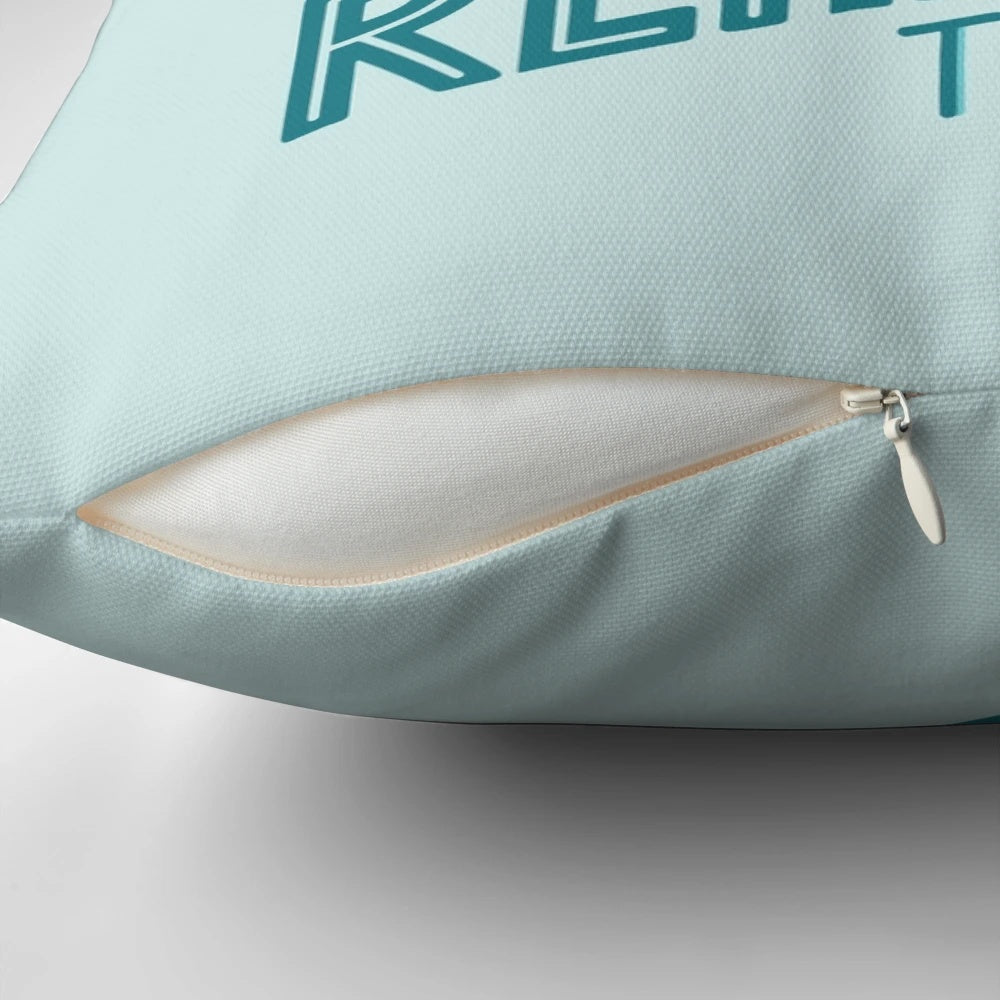 A blue and turquoise throw pillow with the text "Reality Vs. Reading" and a book nerd quote.