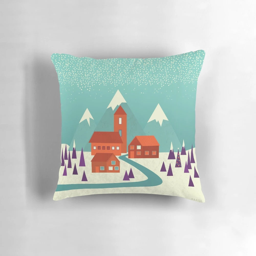 Cozy village landscape pillow in teal, purple, and orange hues with snowy houses and trees