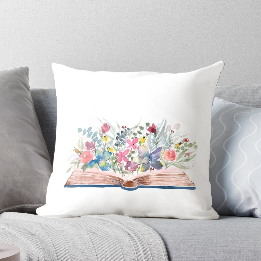 Watercolor painting of an open book with colorful floral elements on a soft, plush pillow.