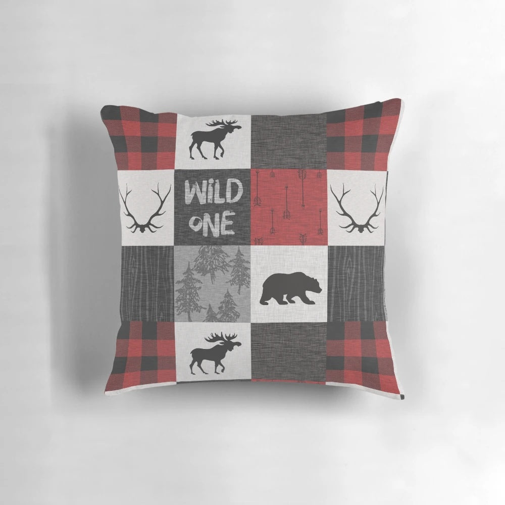 A vibrant red, black, and grey patchwork pillow with a woodland animal design, perfect for a rustic cabin or lodge.