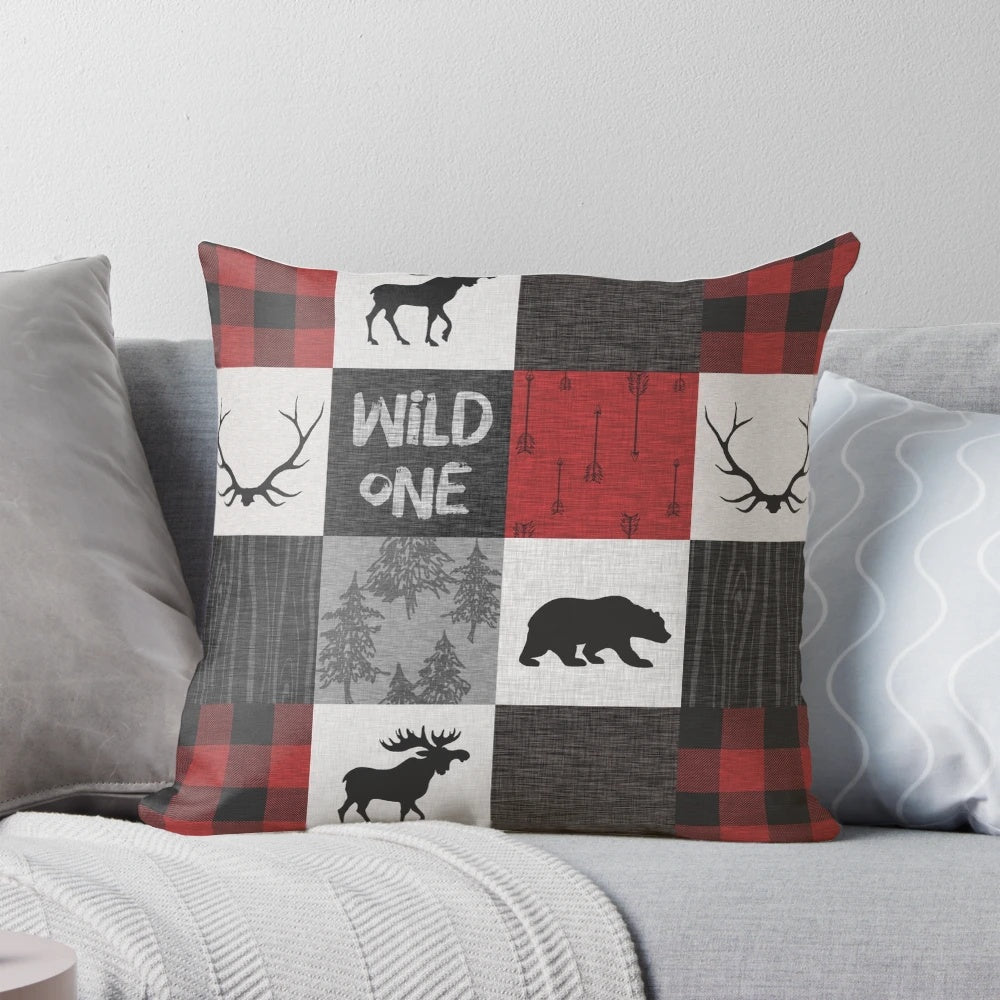 A vibrant red, black, and grey patchwork pillow with a woodland animal design, perfect for a rustic cabin or lodge.