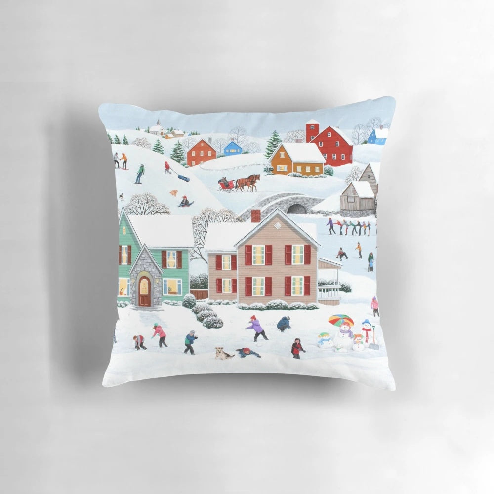 A soft, plush pillow featuring a winter scene with a snowman, trees, and a house in the snow.