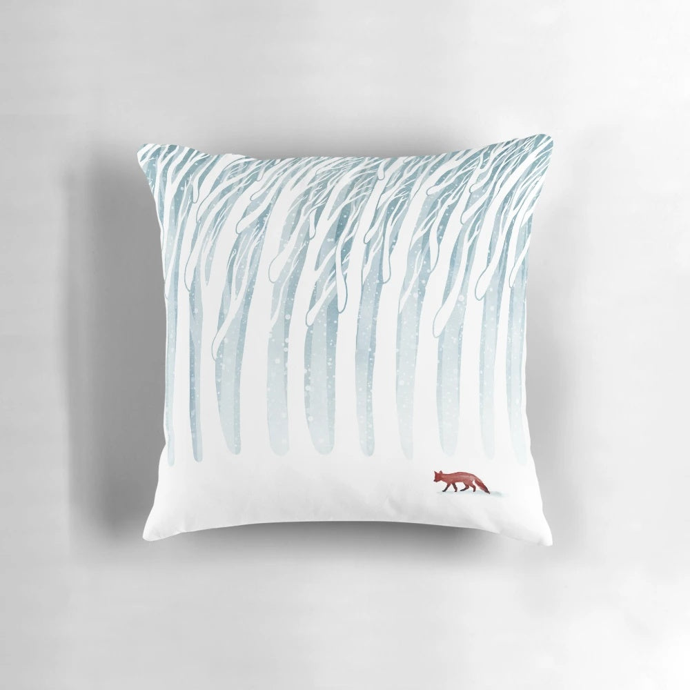 A plush, decorative pillow featuring a winter forest scene with a fox, branches, and snow.