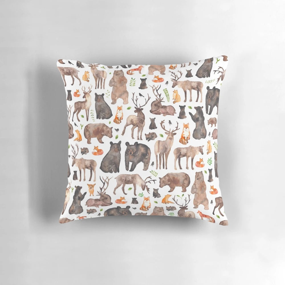 A decorative throw pillow featuring a watercolor pattern of woodland animals like foxes, bears, and deer.