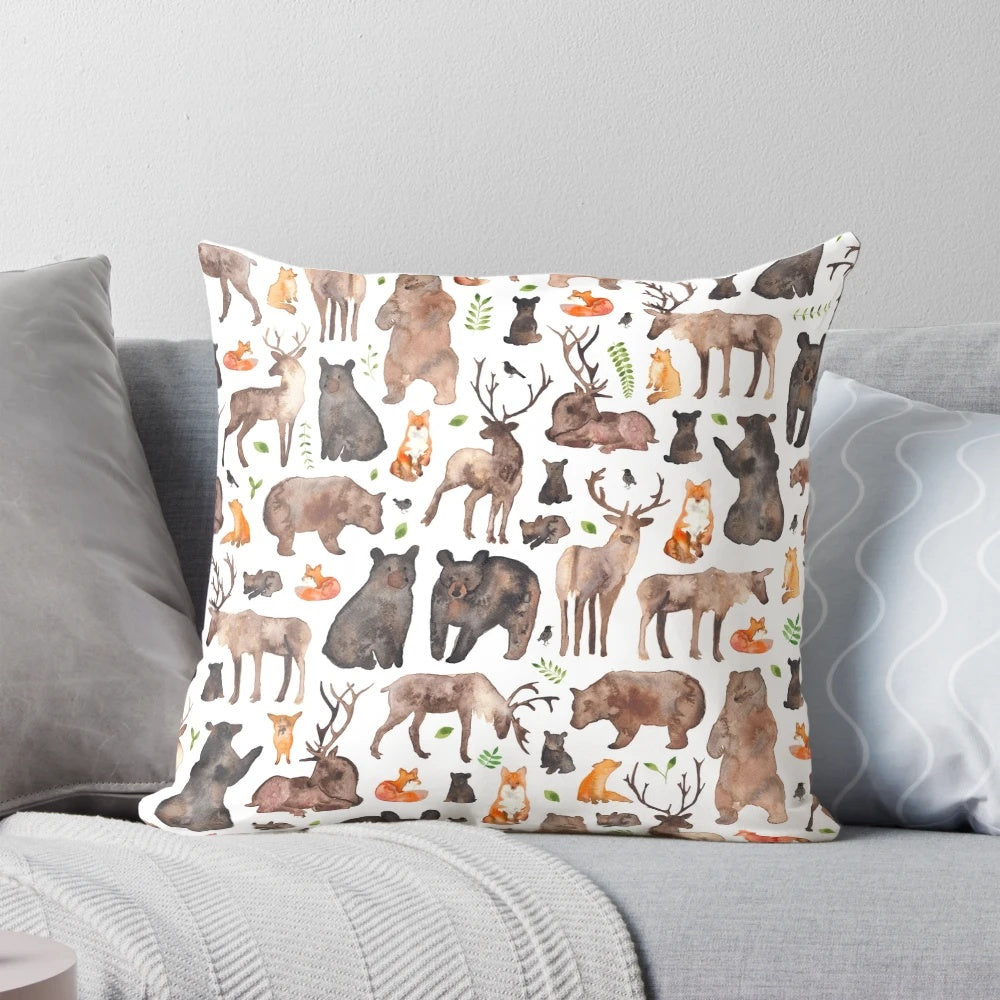 A decorative throw pillow featuring a watercolor pattern of woodland animals like foxes, bears, and deer.