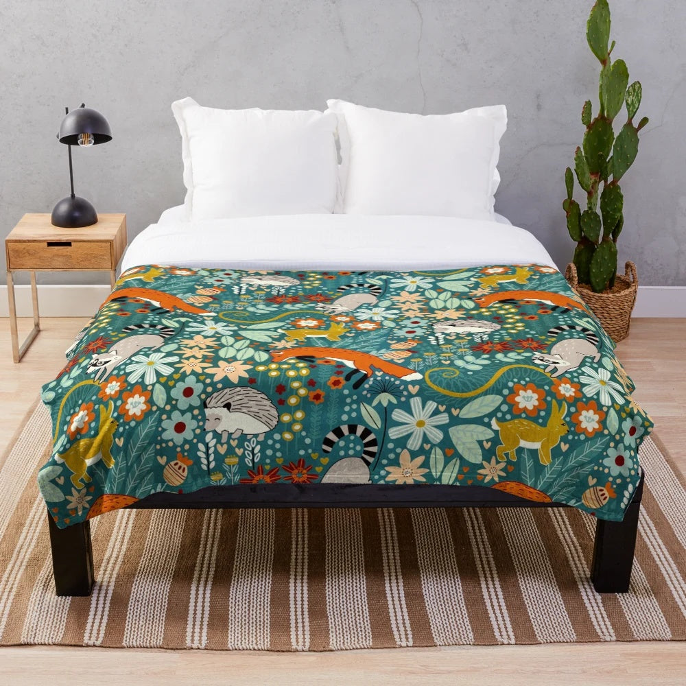 Textured plush blanket featuring a woodland pattern with foxes, raccoons, and other cute forest animals
