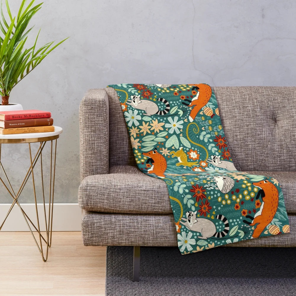 Textured plush blanket featuring a woodland pattern with foxes, raccoons, and other cute forest animals
