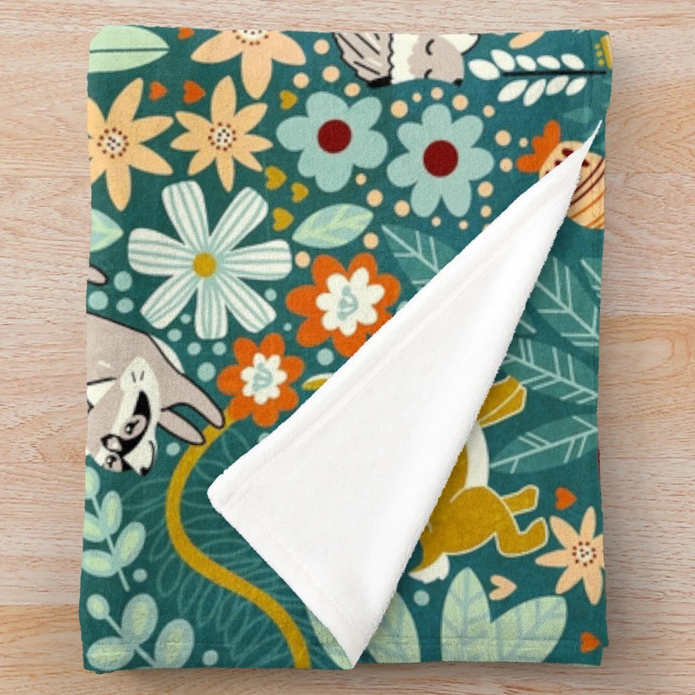 Textured plush blanket featuring a woodland pattern with foxes, raccoons, and other cute forest animals