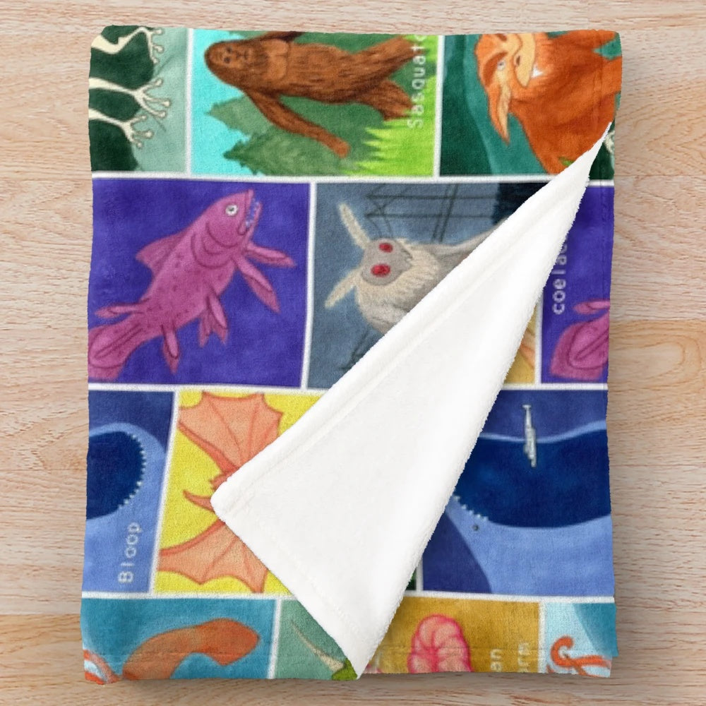 Creepy cute cryptid plush blanket featuring a variety of mysterious creatures
