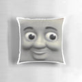 A Thomas the Tank Engine-themed pillow with the character's face prominently displayed, creating a unsettling, meme-worthy design.