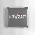 A decorative pillow featuring a cricket-themed design with a howzat, ball, and wicket.