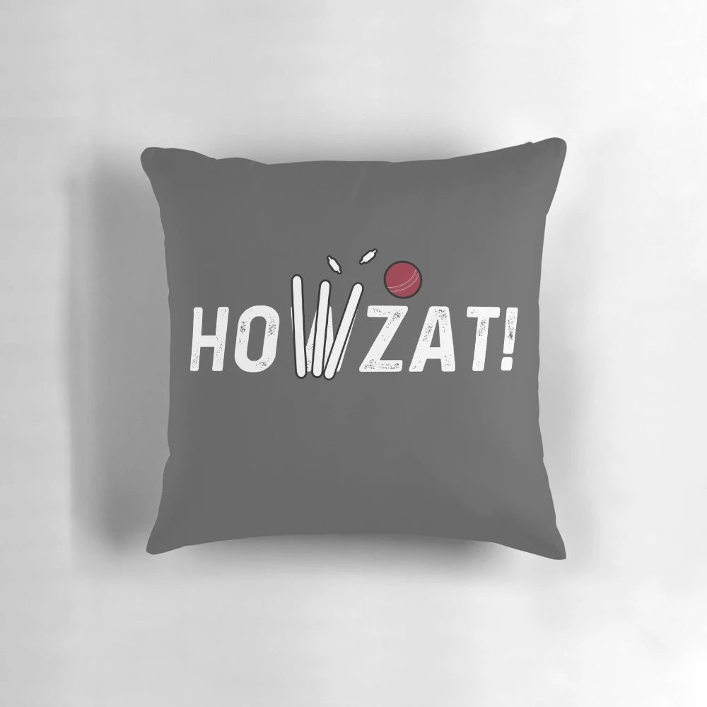 A decorative pillow featuring a cricket-themed design with a howzat, ball, and wicket.