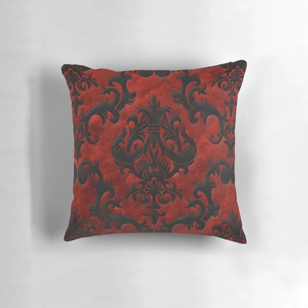 A decorative red and black throw pillow with a gothic, spooky pattern.