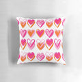 A decorative pink and orange heart-shaped pillow with a preppy, layered heart design.