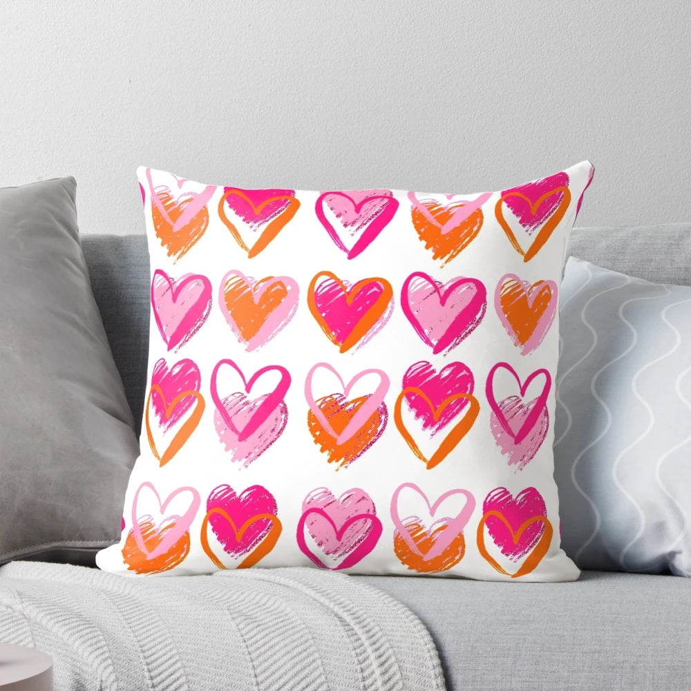 A decorative pink and orange heart-shaped pillow with a preppy, layered heart design.