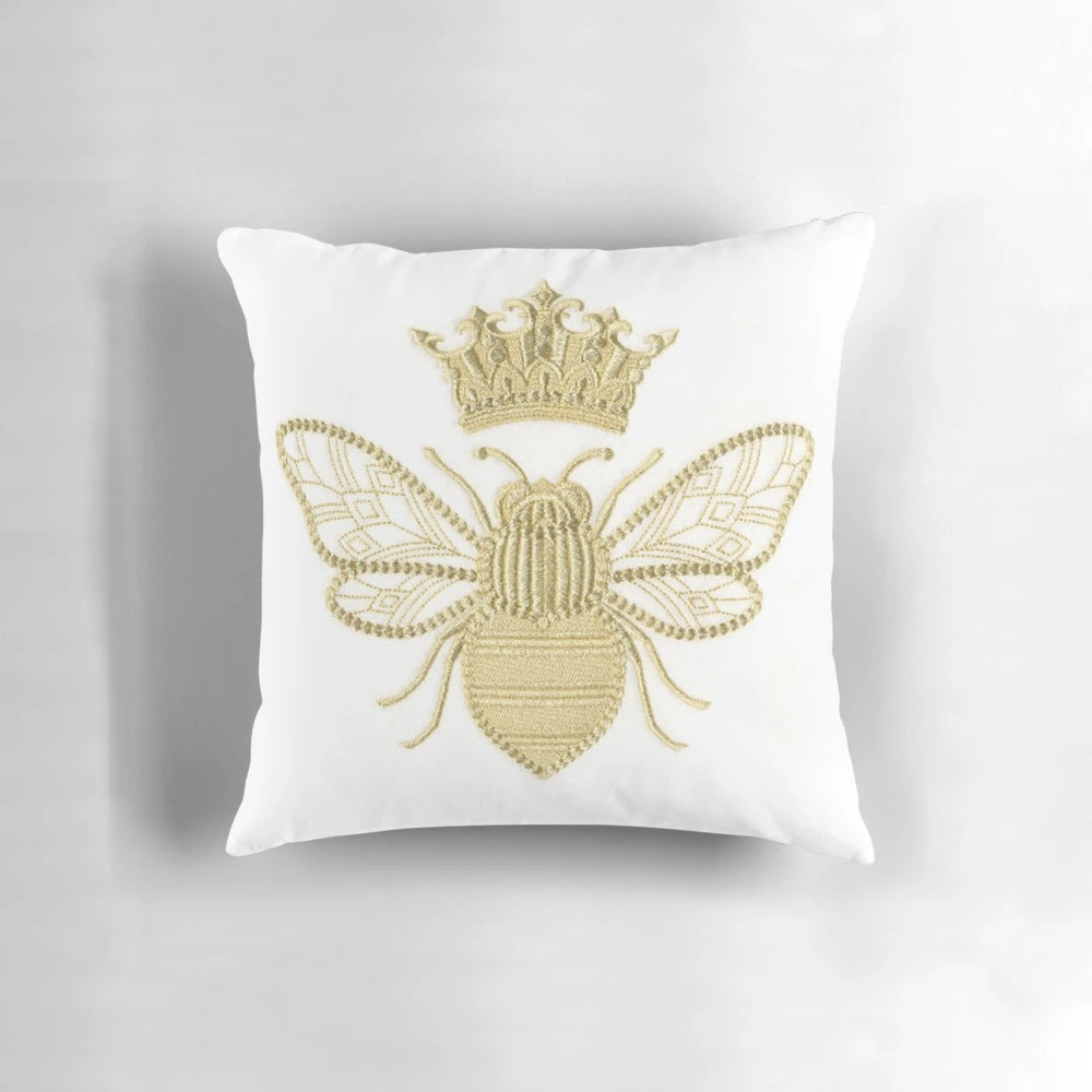 A gold and white embroidered pillow with a beautiful queen bee design, perfect for adding a touch of nature-inspired style to your home.