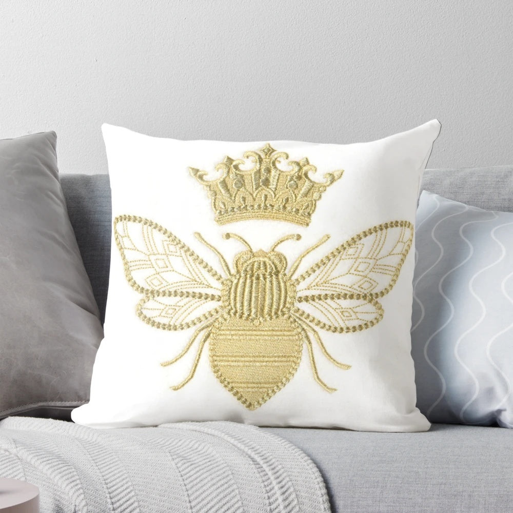 A gold and white embroidered pillow with a beautiful queen bee design, perfect for adding a touch of nature-inspired style to your home.