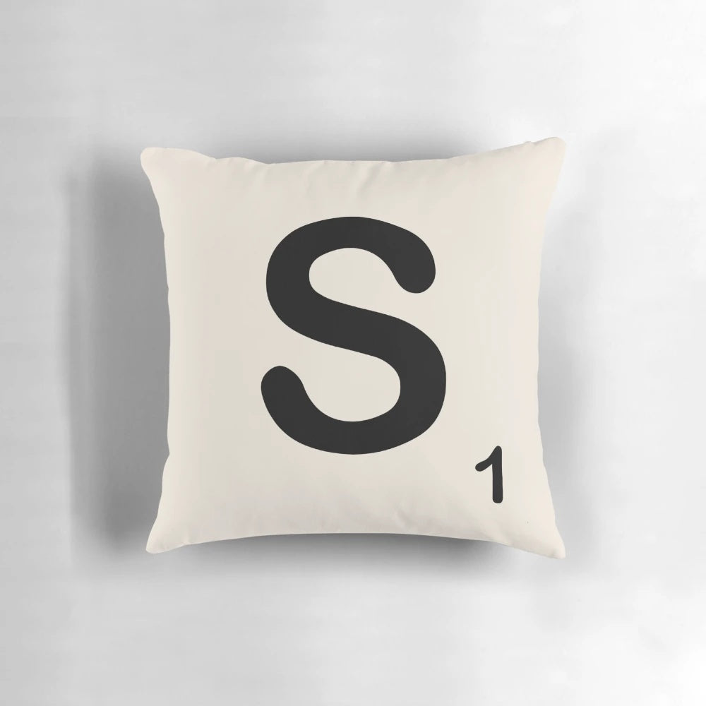 A decorative pillow featuring a stylized Scrabble letter 'S' in a modern, minimalist design.
