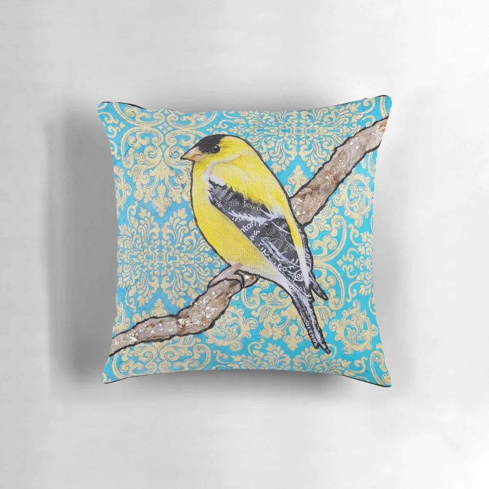 A decorative throw pillow featuring a vibrant illustration of a yellow and black songbird, such as a goldfinch, surrounded by a floral and metallic design.