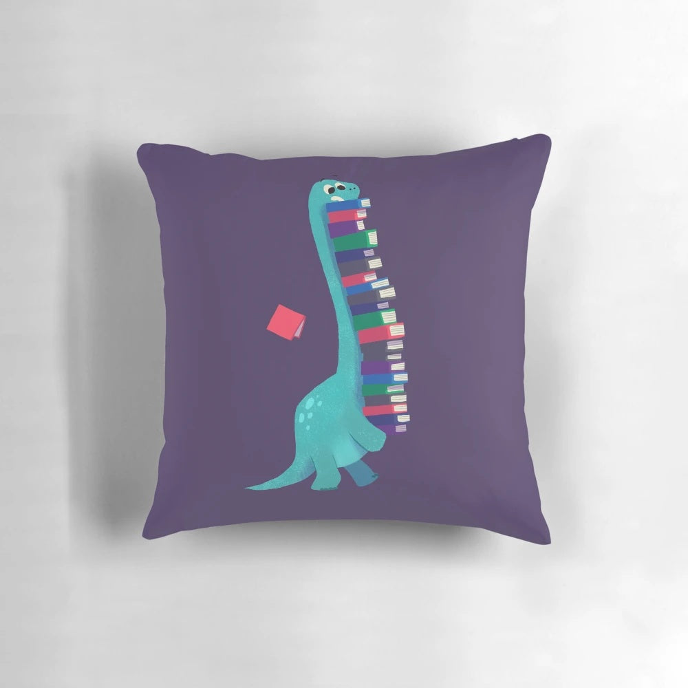 A soft, plush pillow featuring a dinosaur and book design, perfect for kids' rooms.