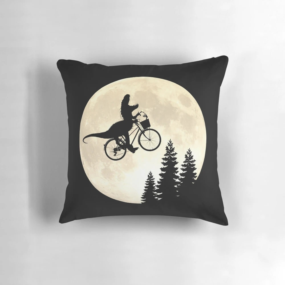 A close-up image of a colorful and whimsical pillow featuring a dinosaur, bicycle, and alien motif.