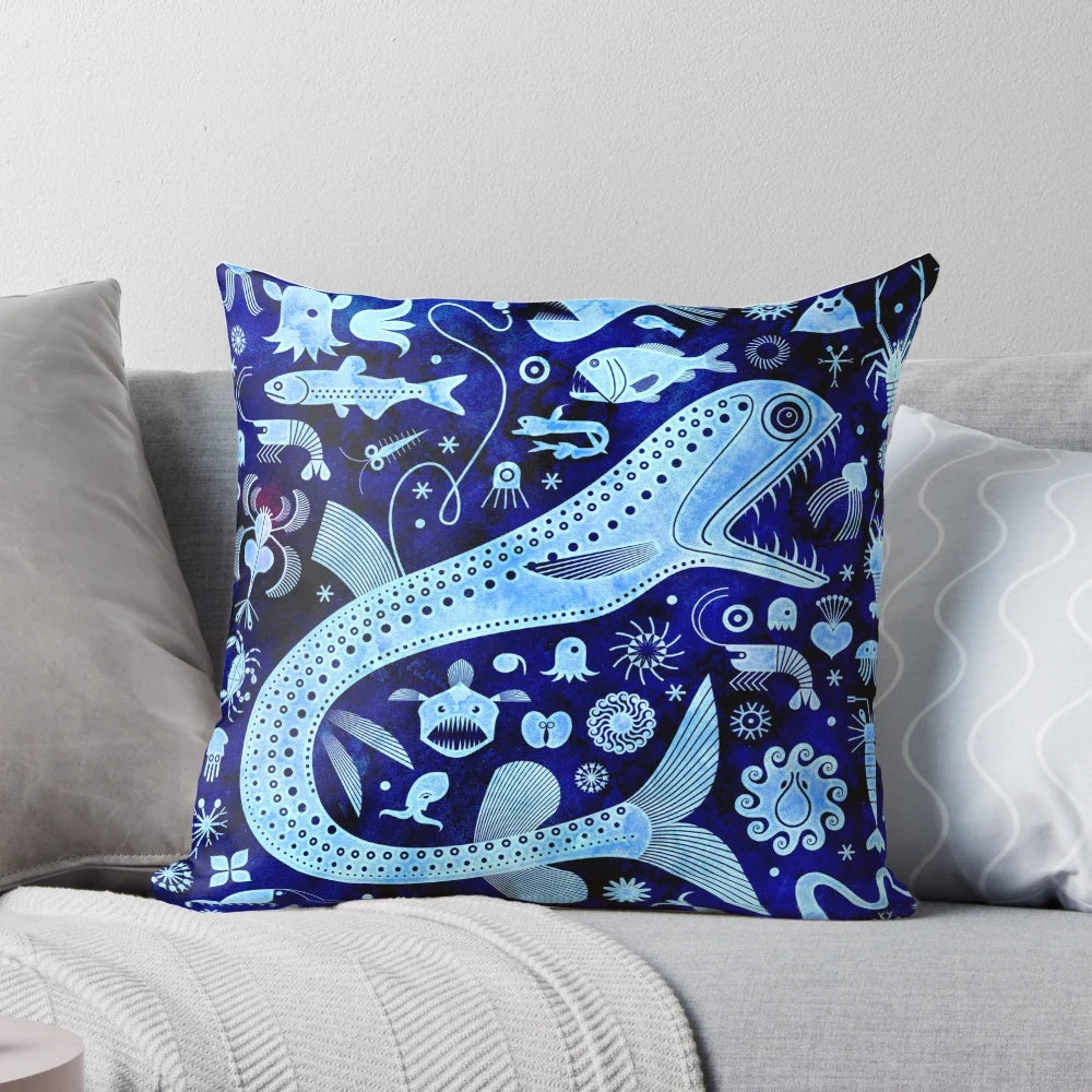 A decorative pillow featuring vibrant illustrations of deep sea creatures like anglerfish, jellyfish, and squid.