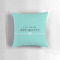 Two pink and teal pillows with a breakfast-themed design, featuring donuts, cakes, and Tiffany-style branding.