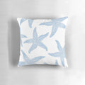 A decorative pillow featuring a vibrant watercolor painting of dancing blue starfish against a soft, white background.