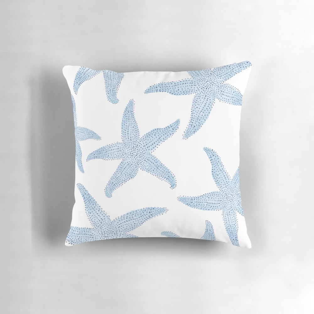 A decorative pillow featuring a vibrant watercolor painting of dancing blue starfish against a soft, white background.