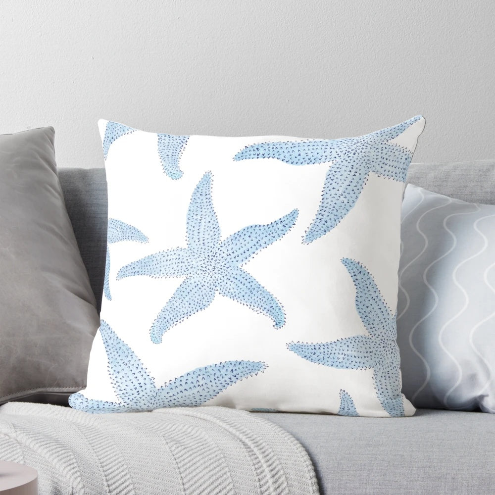 A decorative pillow featuring a vibrant watercolor painting of dancing blue starfish against a soft, white background.