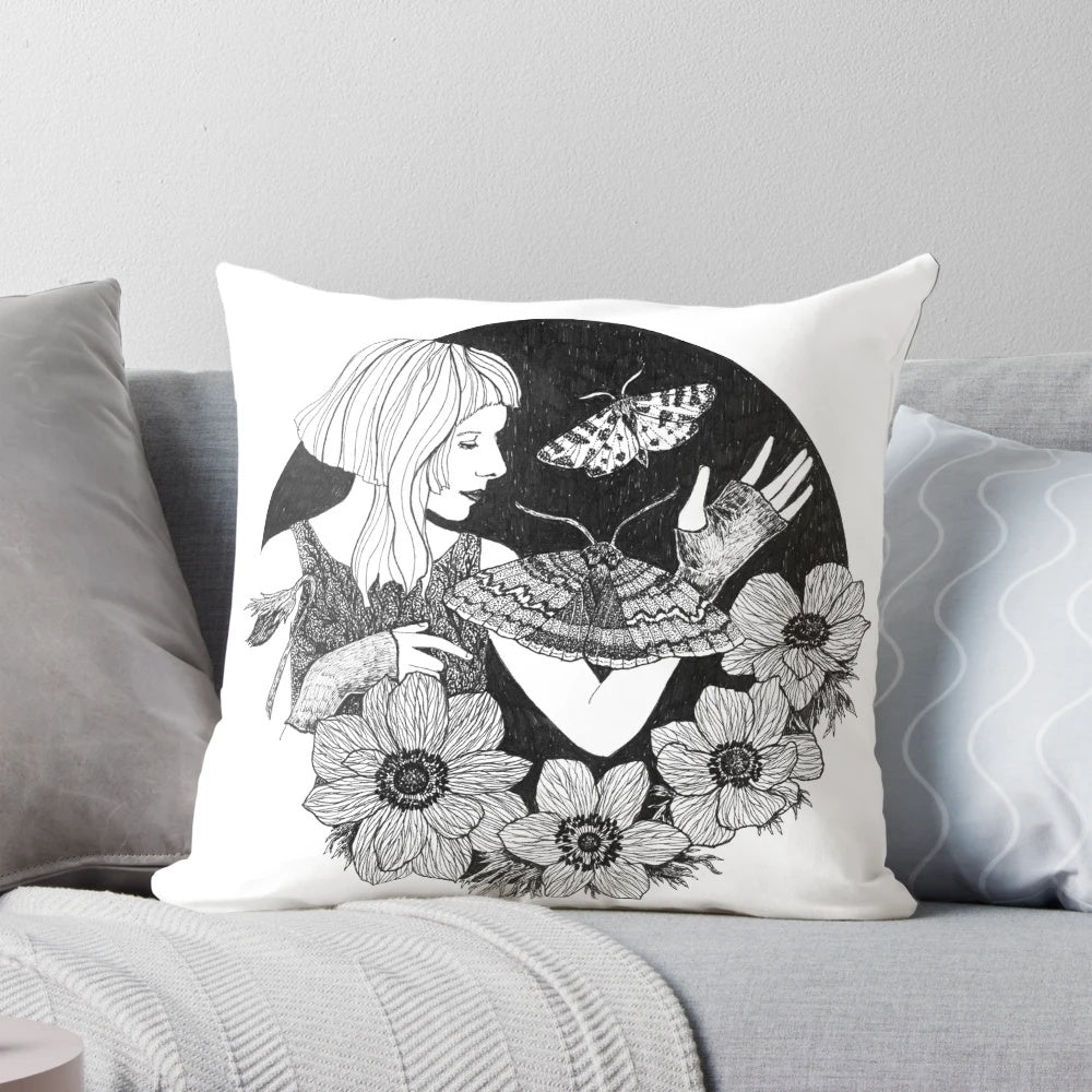 Moody black and white portrait of a woman surrounded by ethereal flowers and butterflies on a decorative pillow