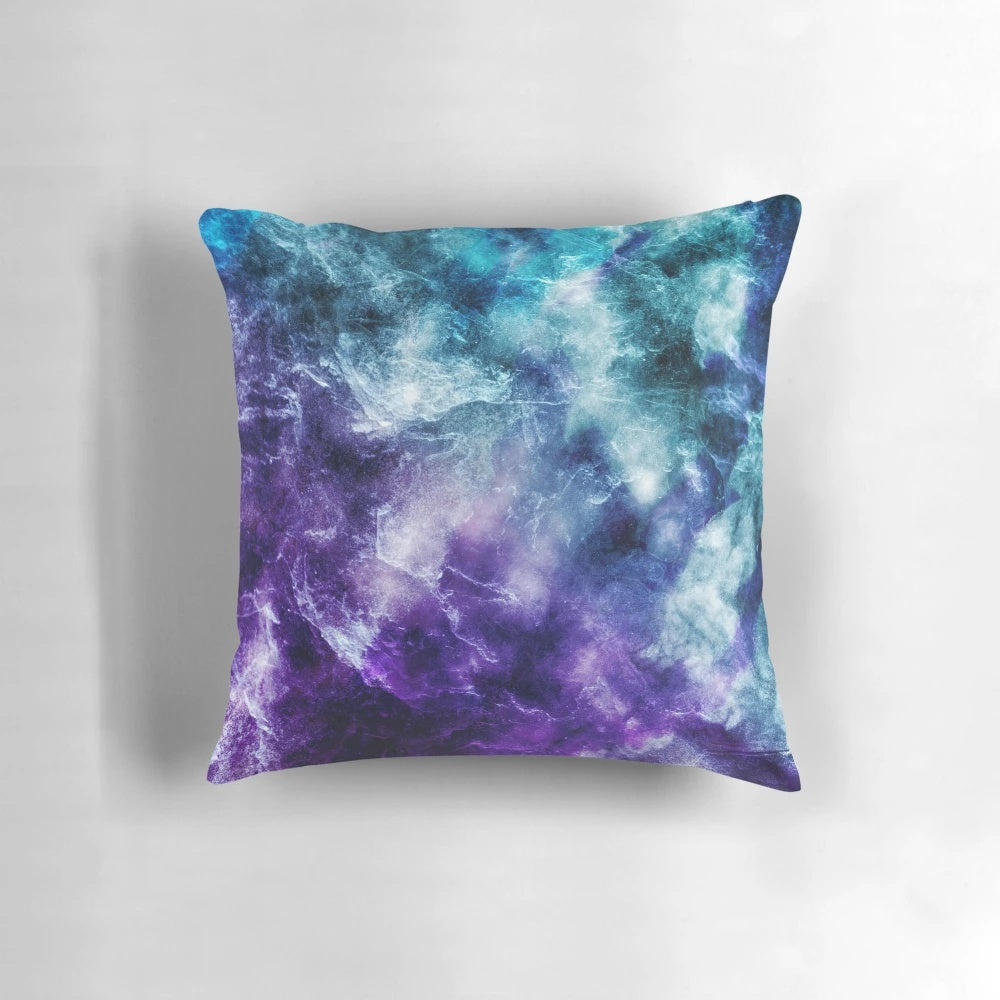A plush, decorative pillow featuring a captivating galaxy nebula and marble print design in shades of purple and teal.