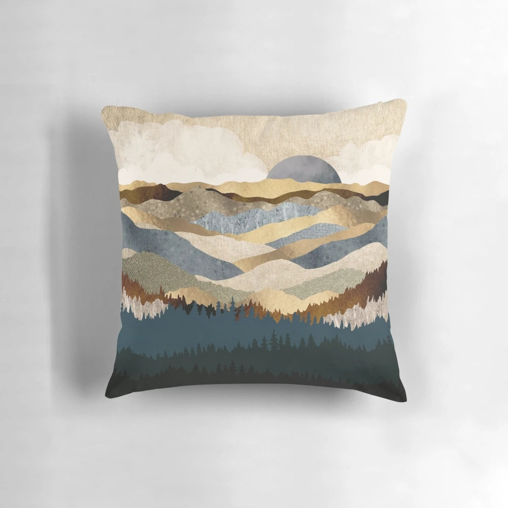 A golden, abstract landscape pillow featuring mountains, trees, and a serene vista.