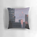 A soft, plush pillow featuring a cute pixel art cityscape with a violet cat, in a pastel sunset color palette.