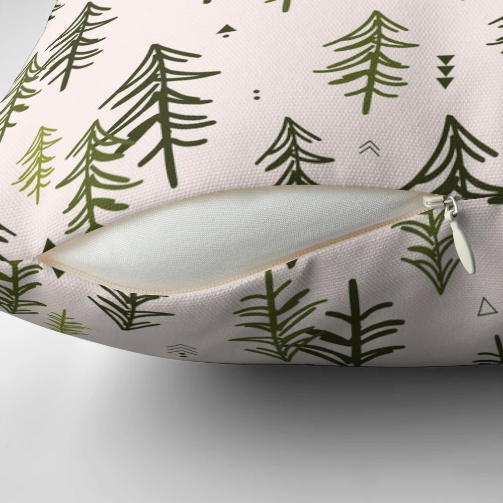 A decorative throw pillow featuring a hand-drawn pattern of stylized fir trees in shades of green.