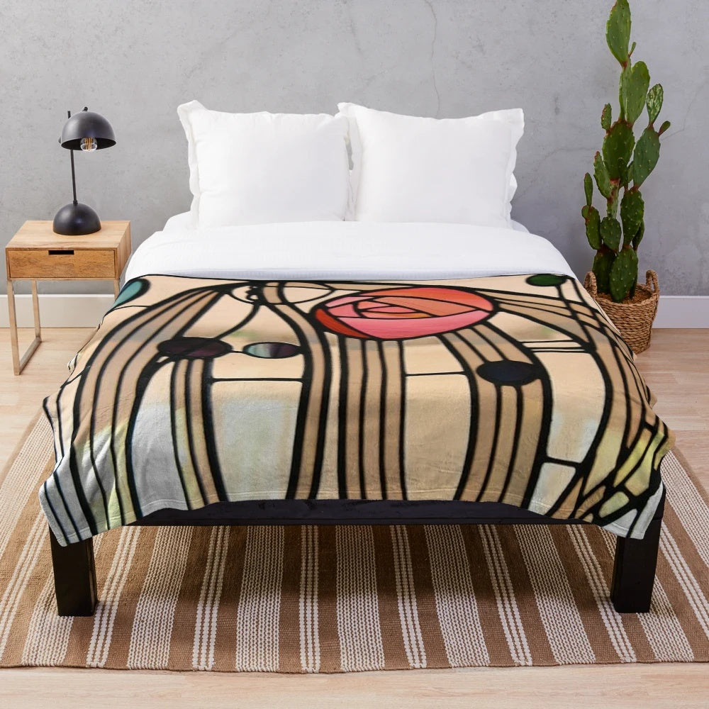 A plush blanket featuring the iconic Mackintosh rose design, inspired by the art nouveau style of Charles Rennie Mackintosh.