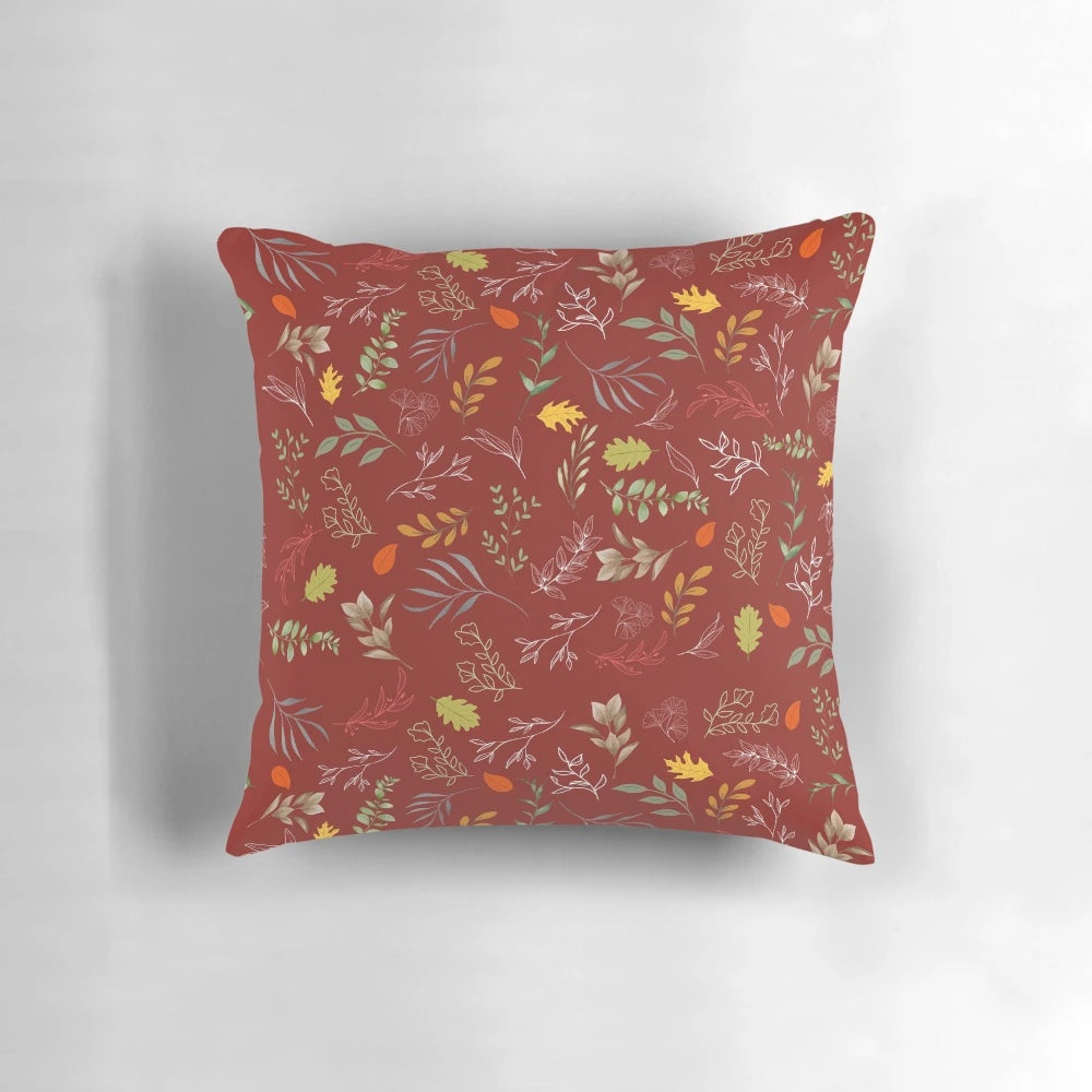 Autumn foliage-inspired throw pillow with red and green leaves on a neutral background