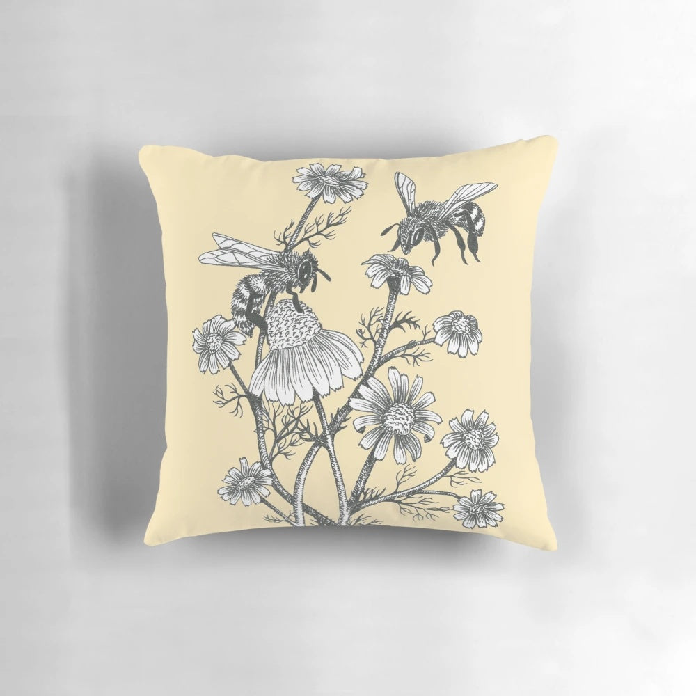 Pillow featuring a black and white ink drawing of bees and chamomile flowers on a honey-colored background