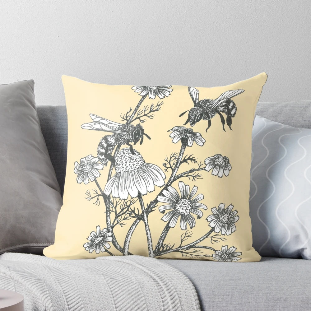 Pillow featuring a black and white ink drawing of bees and chamomile flowers on a honey-colored background