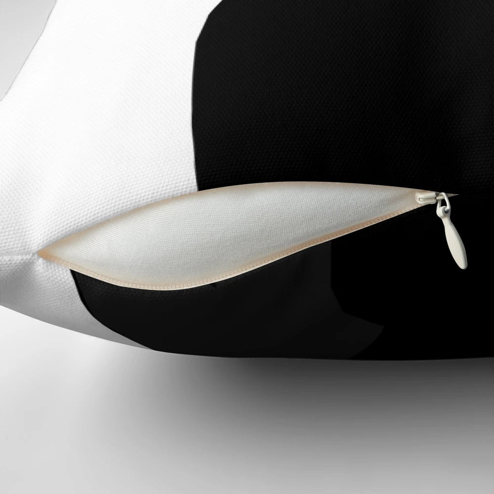 A black cat peeking out from a plush, comfortable pillow