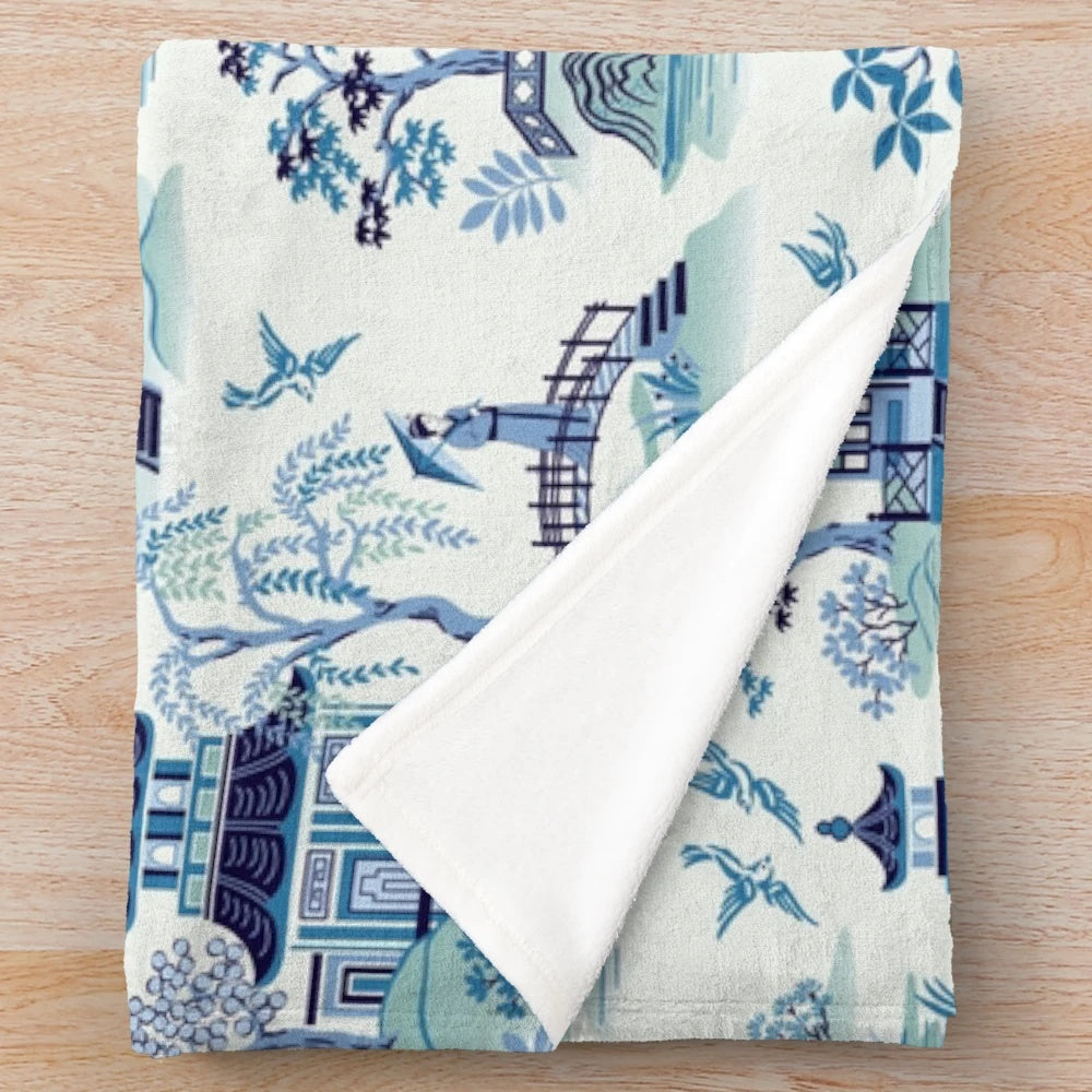 Chinoiserie-style blue plush blanket with pagoda and willow pattern design
