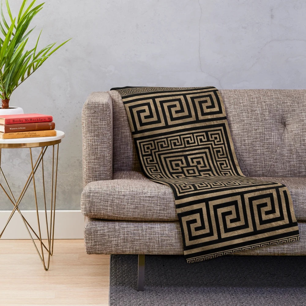 Greek key meander pattern printed on a black and gold plush blanket