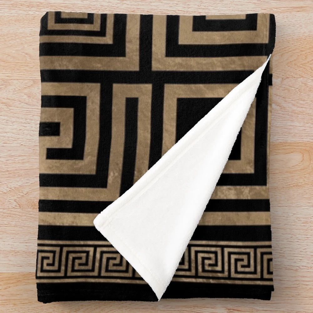 Greek key meander pattern printed on a black and gold plush blanket