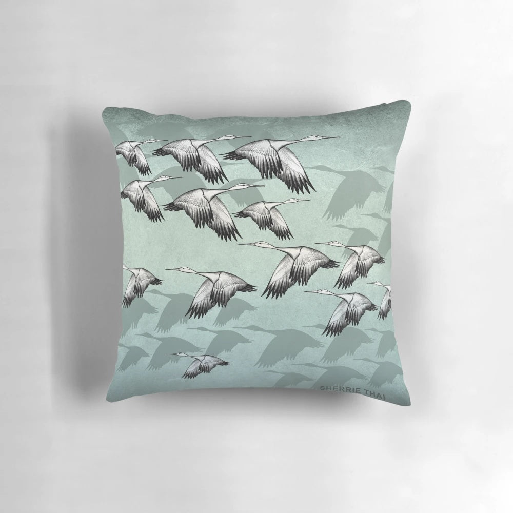 Decorative Japanese-inspired throw pillow featuring a pattern of graceful flying cranes in shades of green and earthy tones.