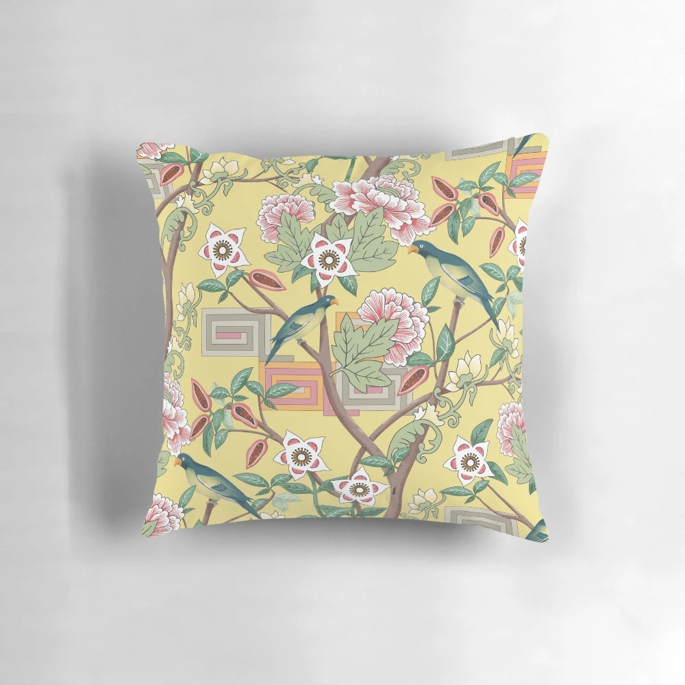 A beautiful decorative pillow featuring a chinoiserie-inspired design with vibrant parrots and peonies on a butter yellow background.
